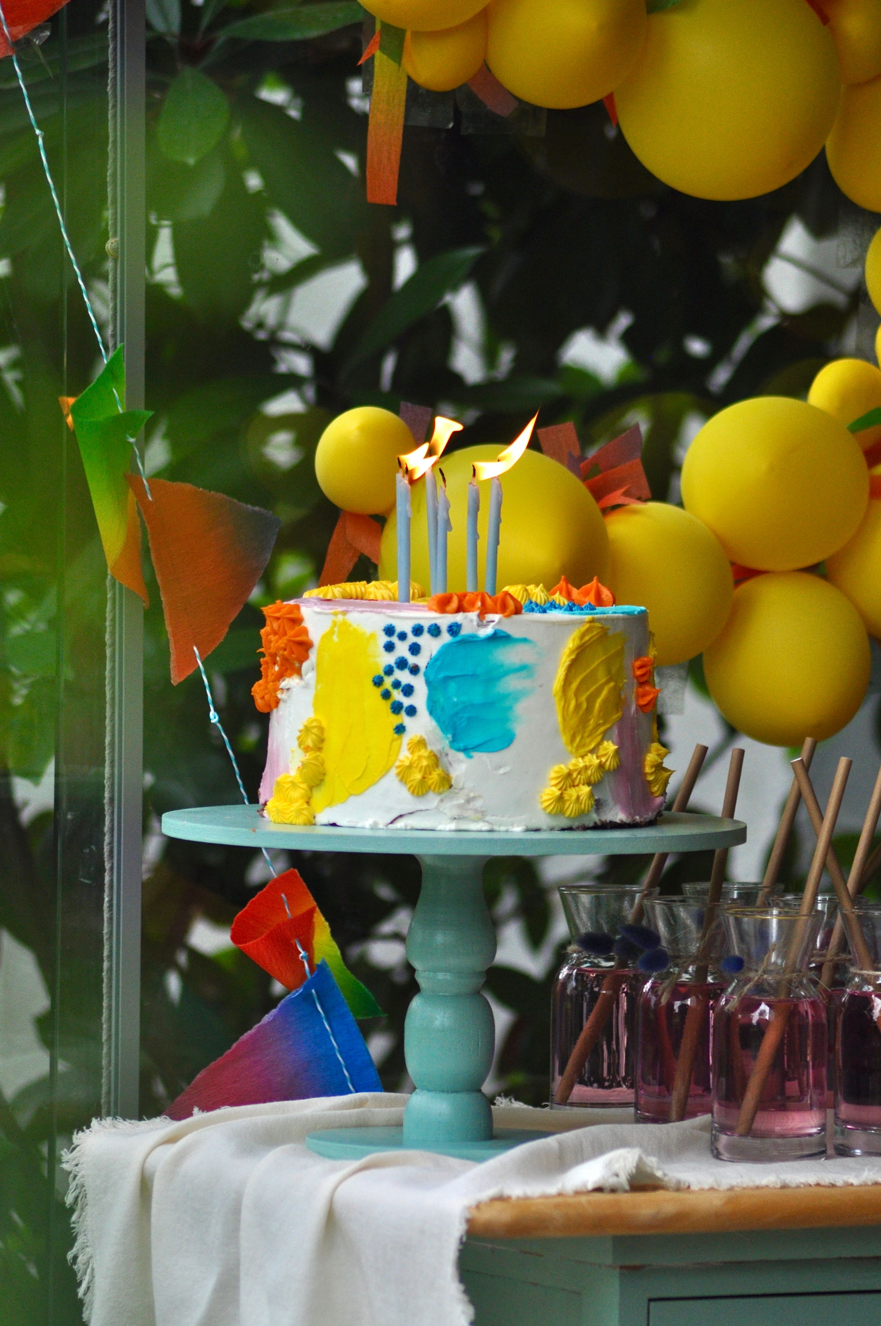 A picture of a cake with colorful frosting and party decor around the cake