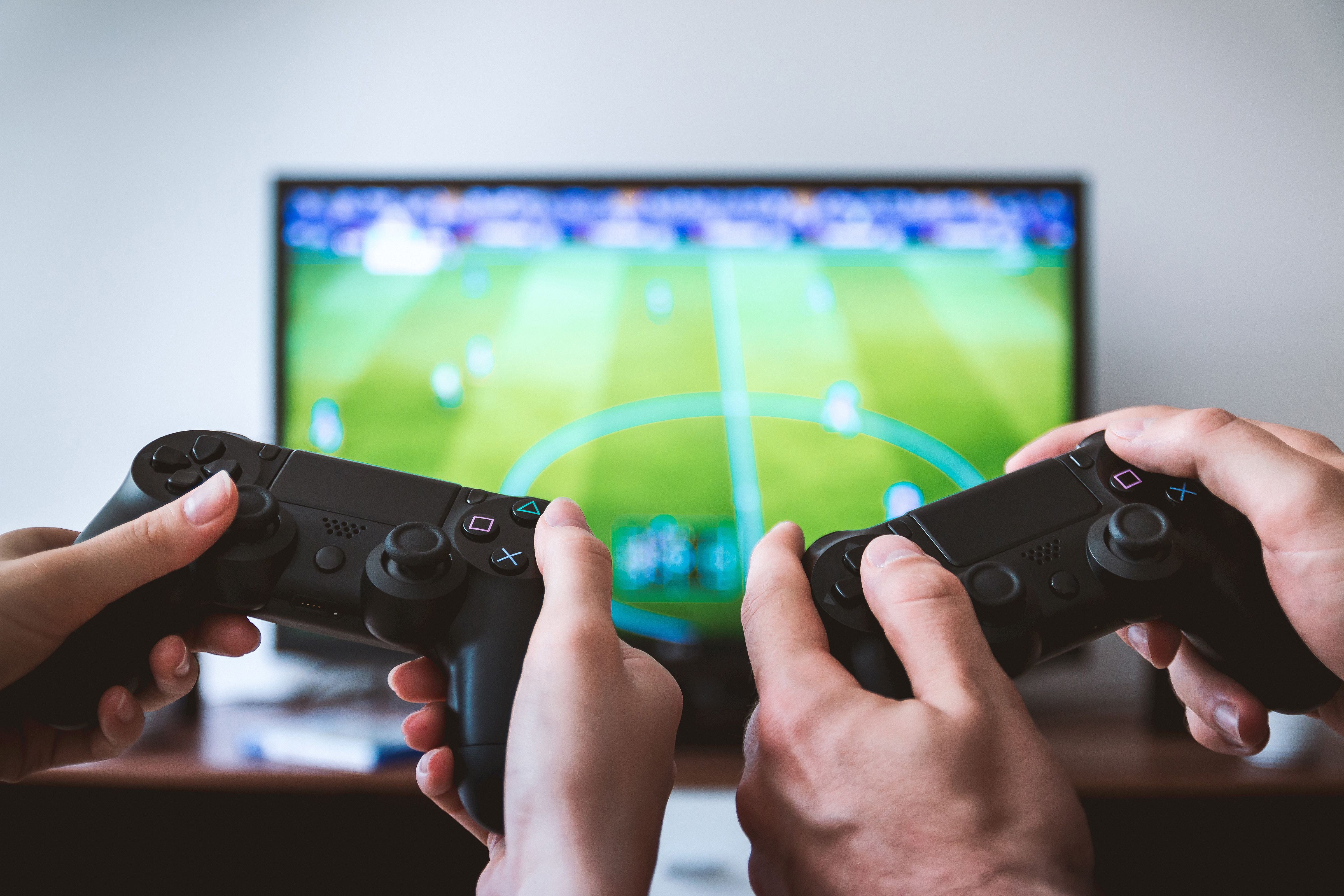 a picture of two people holding controllers playing a sports game.